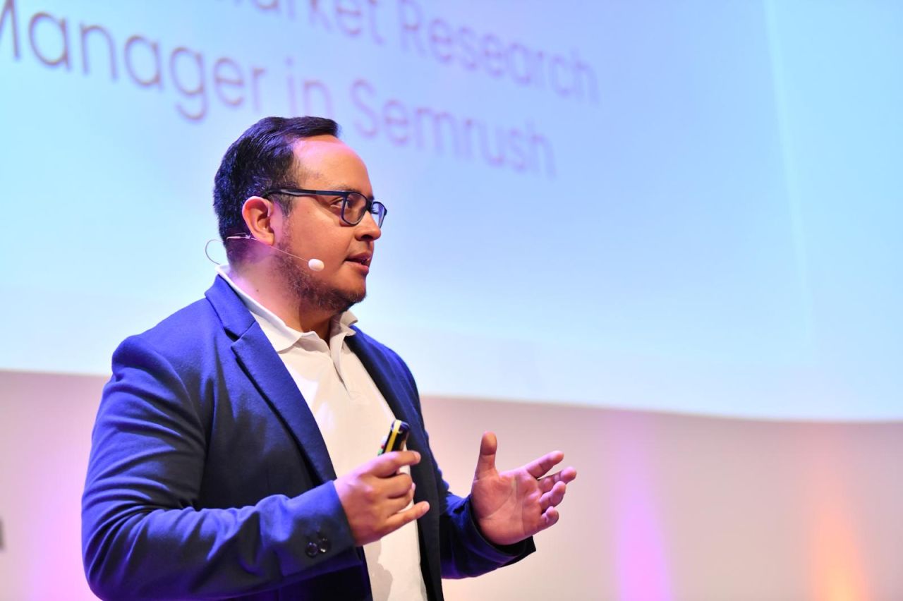 Fernando Angulo presenta una charla sobre SEO y búsqueda con IA en un escenario de Berlín