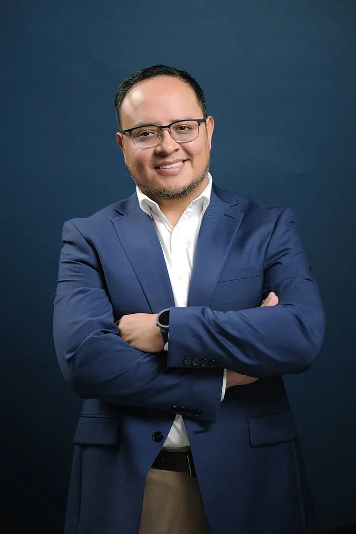 Fernando Angulo de frente, brazos cruzados, fondo de estudio azul marino